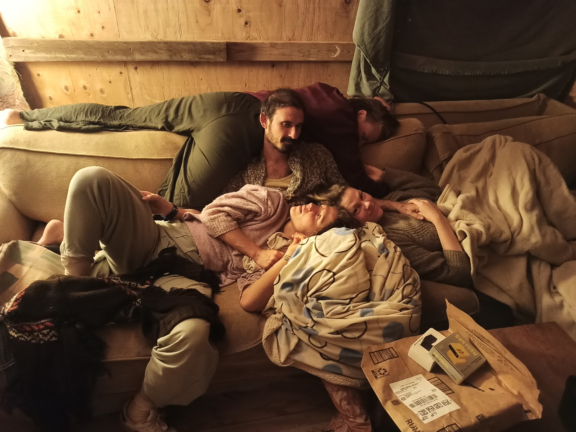 Campmates cuddled together on a couch in warm lamplight
